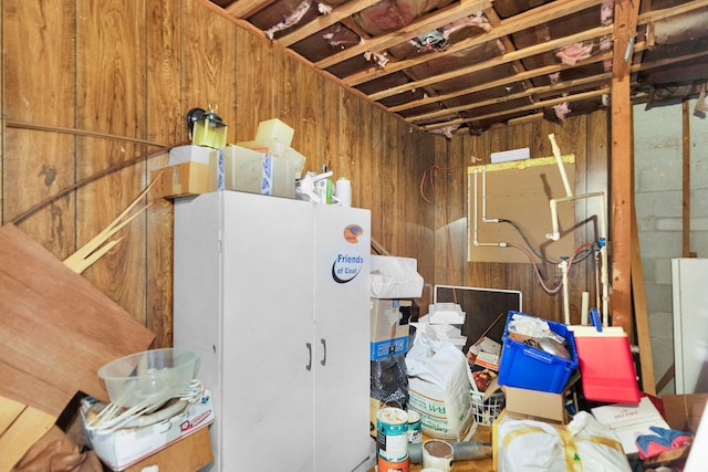 basement featuring refrigerator and wood walls