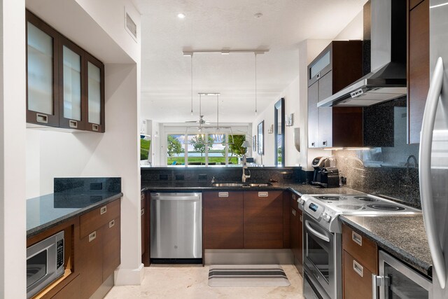 kitchen with appliances with stainless steel finishes, pendant lighting, sink, backsplash, and wall chimney range hood