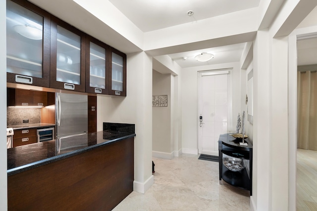 bar with wine cooler, decorative backsplash, dark brown cabinetry, and stainless steel refrigerator