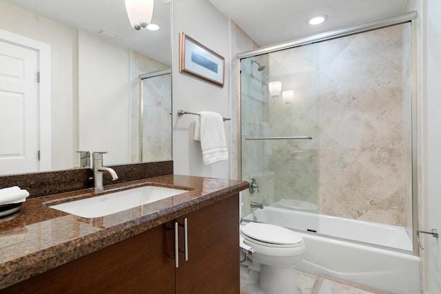 full bathroom featuring vanity, combined bath / shower with glass door, and toilet