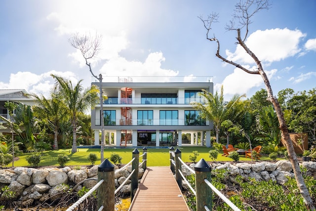 rear view of property with a balcony and a yard