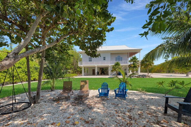 back of property with a carport, a balcony, and a lawn