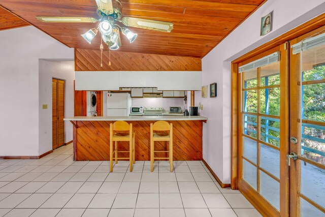 kitchen featuring vaulted ceiling, stacked washer and dryer, white fridge, wood ceiling, and kitchen peninsula