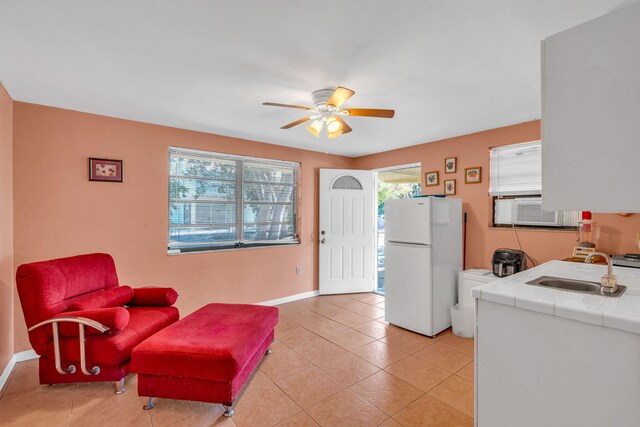 interior space with sink, light tile patterned floors, white refrigerator, tile counters, and ceiling fan