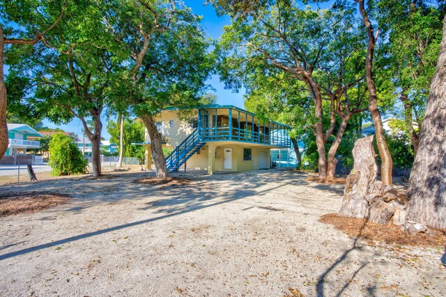 view of front of property featuring stairs, gravel driveway, and stucco siding