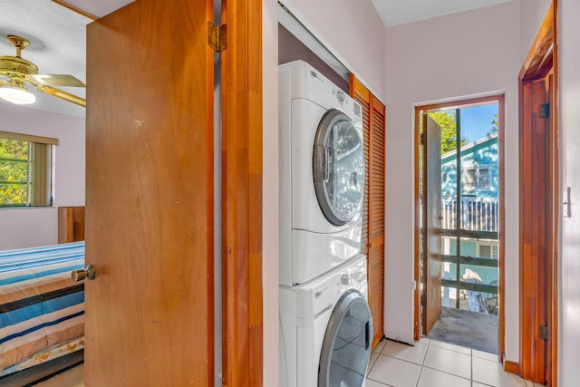 laundry room featuring ceiling fan, stacked washer and dryer, a healthy amount of sunlight, and light tile patterned floors