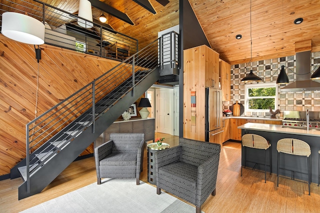 living area with stairway, wood ceiling, light wood-style floors, and high vaulted ceiling