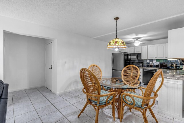 dining space featuring sink, light tile patterned floors, and a textured ceiling