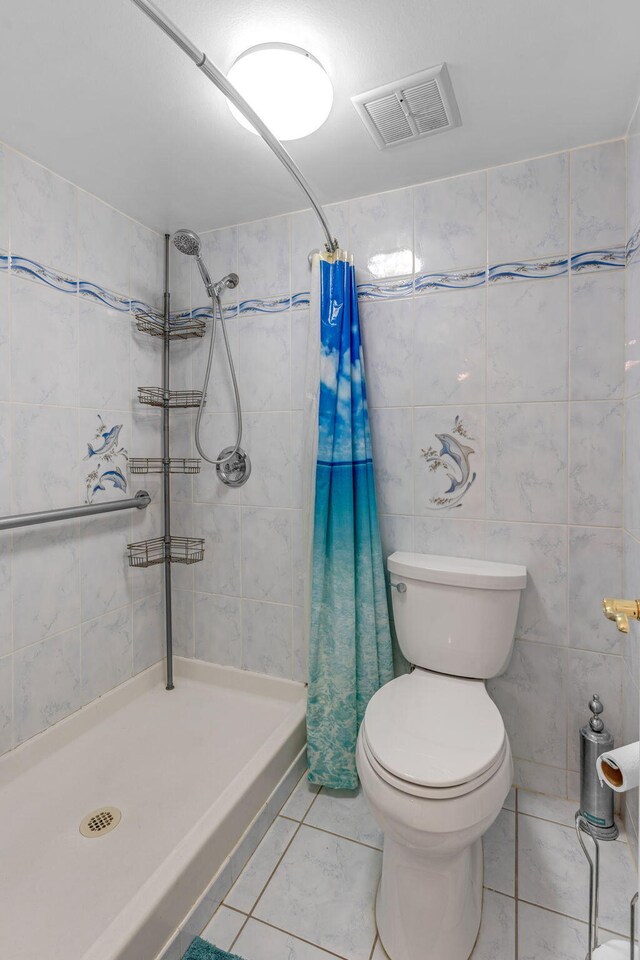 bathroom with tile patterned flooring, toilet, tile walls, and walk in shower