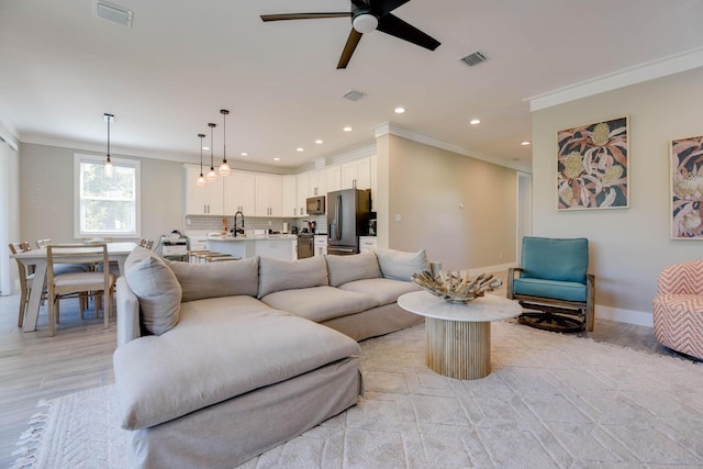 living area with baseboards, visible vents, and crown molding