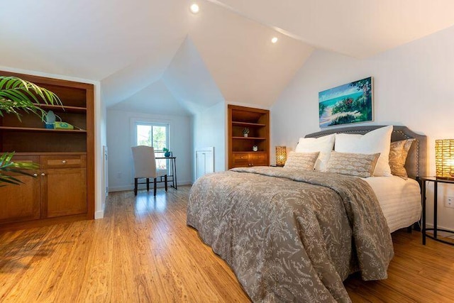 bedroom with vaulted ceiling, light wood-style floors, and baseboards