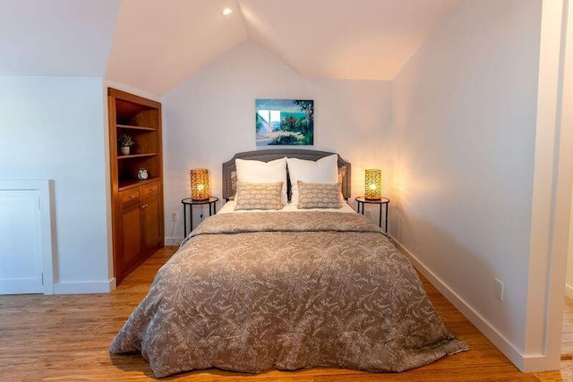 bedroom with baseboards, lofted ceiling, and light wood-style flooring