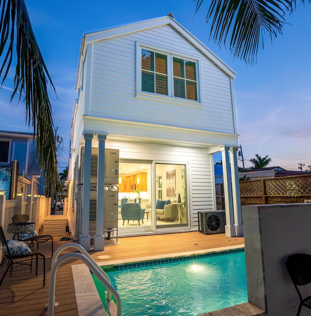 back of house with a deck, ac unit, and a fenced in pool