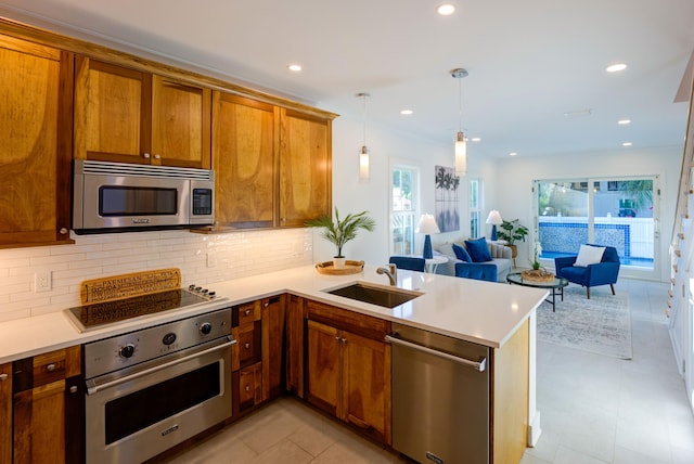 kitchen featuring a peninsula, a sink, open floor plan, appliances with stainless steel finishes, and brown cabinets