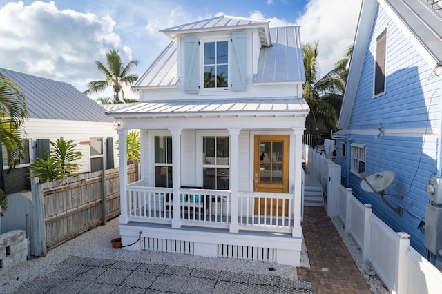 view of front of house with covered porch, metal roof, a standing seam roof, and fence