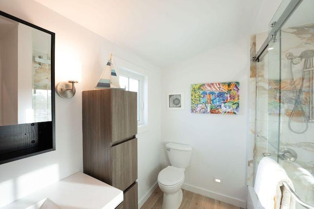 bathroom with wood finished floors, toilet, baseboards, and a shower with shower door