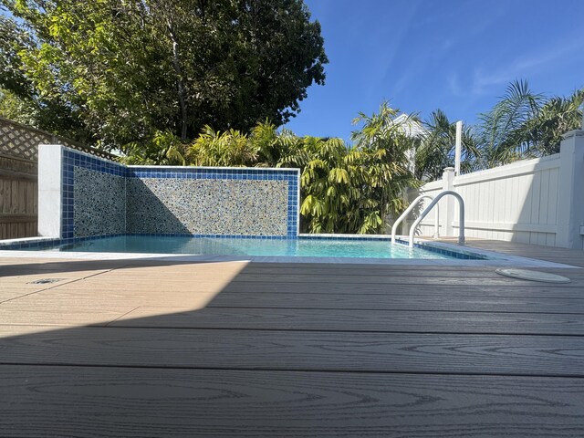outdoor pool with fence and a wooden deck