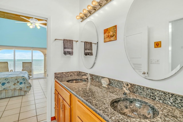 bathroom with a water view, ceiling fan, tile patterned floors, and vanity