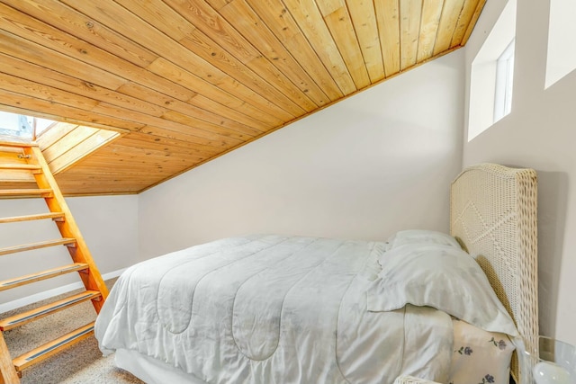 bedroom featuring lofted ceiling with skylight, multiple windows, and wooden ceiling