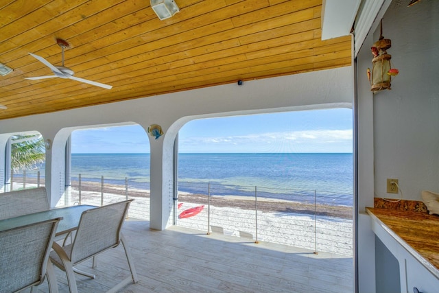 exterior space featuring ceiling fan, a beach view, and a water view