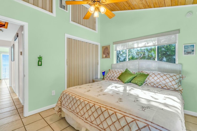 tiled bedroom featuring ceiling fan, a closet, multiple windows, and a towering ceiling