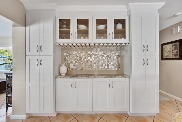 bar with white cabinetry, light stone countertops, light tile patterned floors, and decorative backsplash