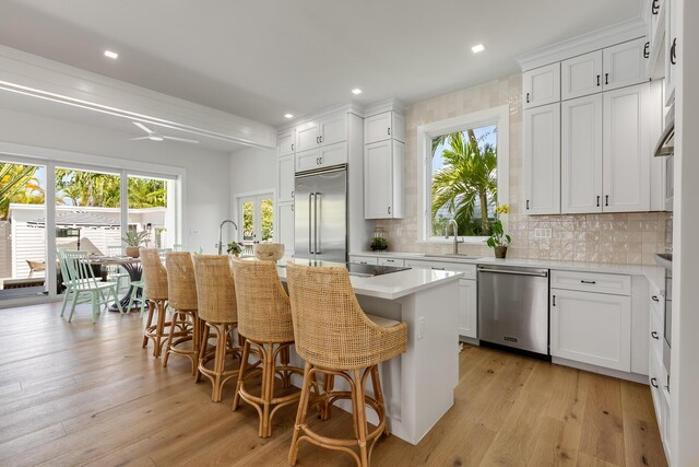 1114 Grinnell St, Key West, FL 33040 - kitchen featuring stainless steel appliances, a kitchen bar, decorative backsplash, white cabinets, and recessed lighting