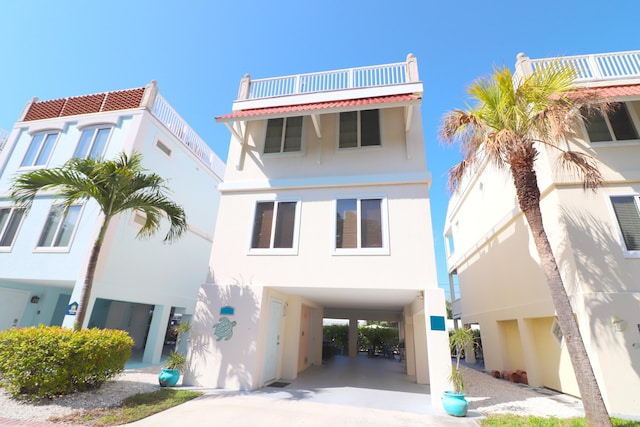 view of front of property featuring driveway, a balcony, a carport, and stucco siding