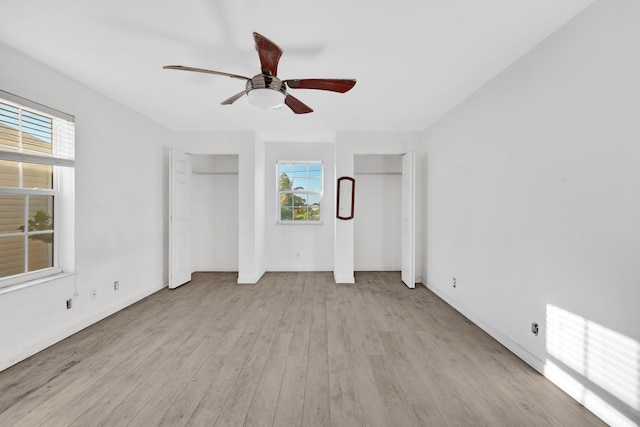 unfurnished bedroom featuring multiple closets, ceiling fan, and light wood-type flooring