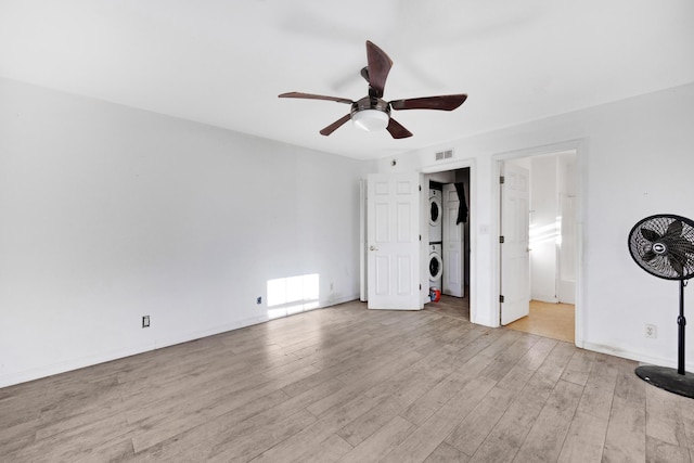 unfurnished bedroom featuring stacked washer / drying machine, ceiling fan, and light hardwood / wood-style flooring