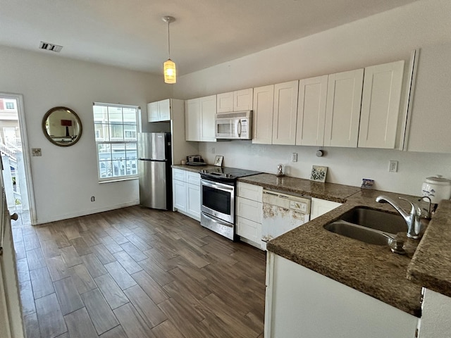 kitchen with sink, appliances with stainless steel finishes, white cabinetry, hanging light fixtures, and dark hardwood / wood-style floors