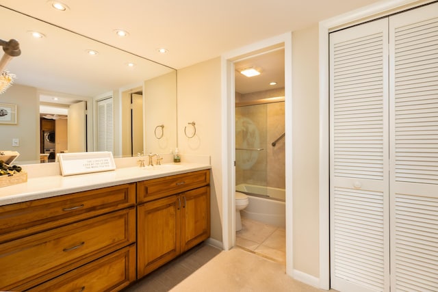 full bathroom with combined bath / shower with glass door, tile patterned flooring, vanity, stacked washer and clothes dryer, and toilet