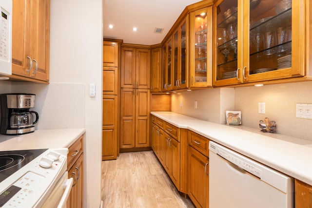 kitchen with backsplash, white appliances, and light wood-type flooring