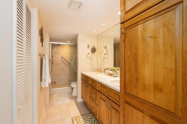 bathroom with tile patterned flooring, vanity, a shower with door, and toilet