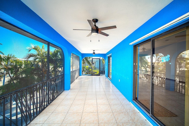 unfurnished sunroom with ceiling fan