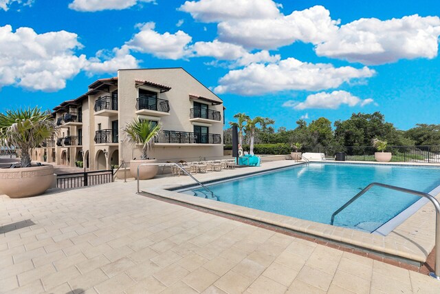 community pool with a patio area and fence