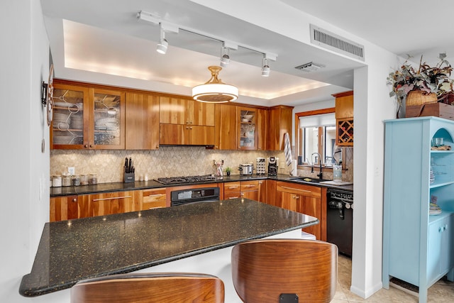 kitchen featuring brown cabinets, visible vents, backsplash, a sink, and black appliances