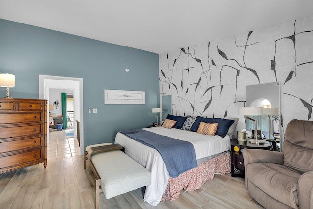 bedroom with an accent wall and wood finished floors