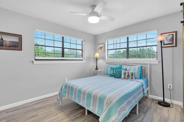 bedroom featuring ceiling fan, hardwood / wood-style floors, and multiple windows