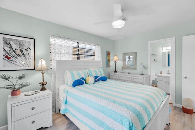 bedroom featuring ceiling fan, ensuite bath, sink, and light hardwood / wood-style flooring