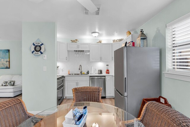 kitchen with sink, backsplash, white cabinets, and appliances with stainless steel finishes