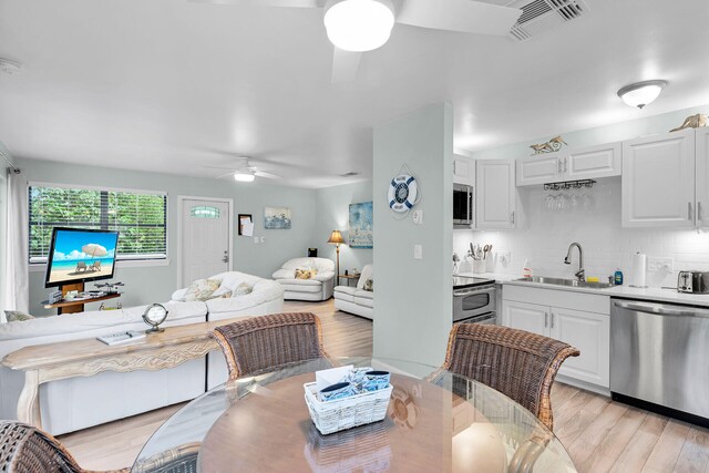 dining room with sink, ceiling fan, and light hardwood / wood-style flooring