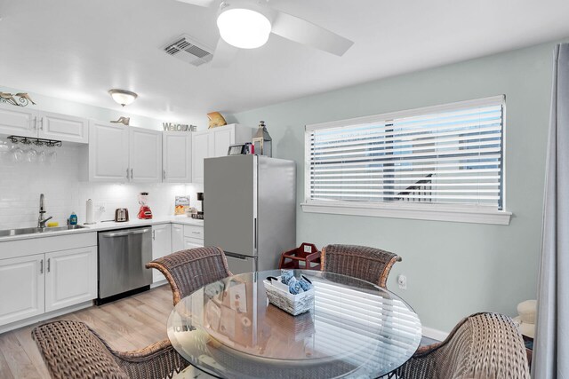 kitchen featuring white cabinetry, sink, backsplash, stainless steel appliances, and plenty of natural light