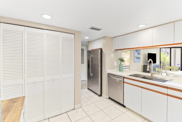 kitchen featuring stainless steel appliances, white cabinetry, sink, and light tile patterned floors