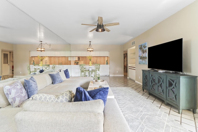 tiled living room featuring ceiling fan with notable chandelier