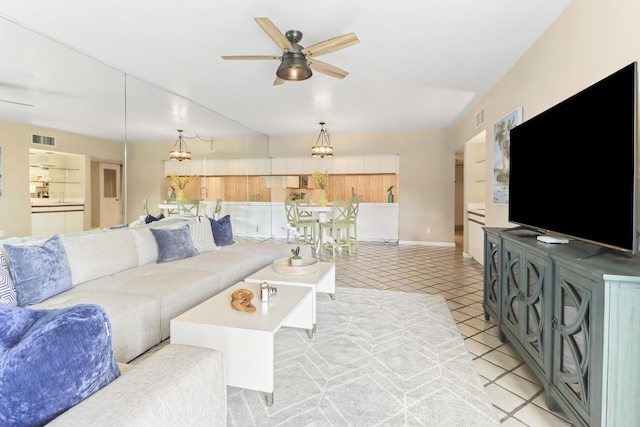 tiled living room with ceiling fan with notable chandelier