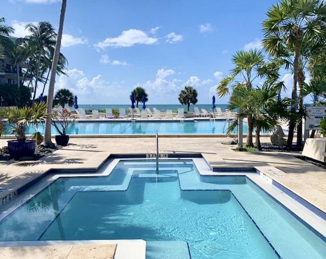 view of swimming pool featuring a patio and a water view