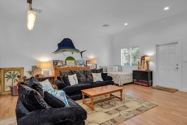 living room with visible vents, ornamental molding, and light wood-style flooring