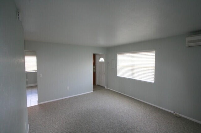 unfurnished room featuring a wall mounted air conditioner and carpet flooring