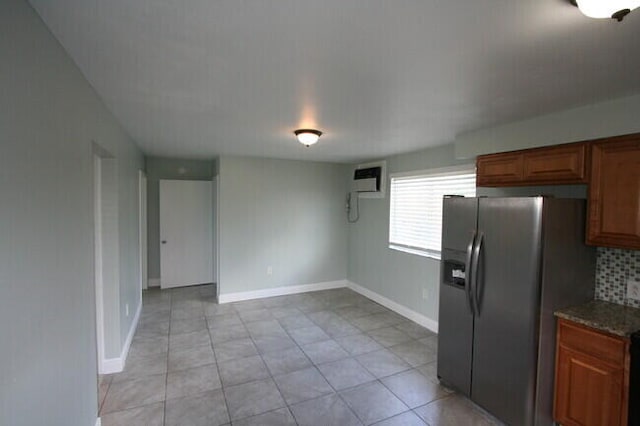 kitchen with light tile patterned floors, a wall mounted AC, stainless steel fridge with ice dispenser, decorative backsplash, and dark stone counters